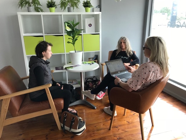 Three people sit around a table, talking