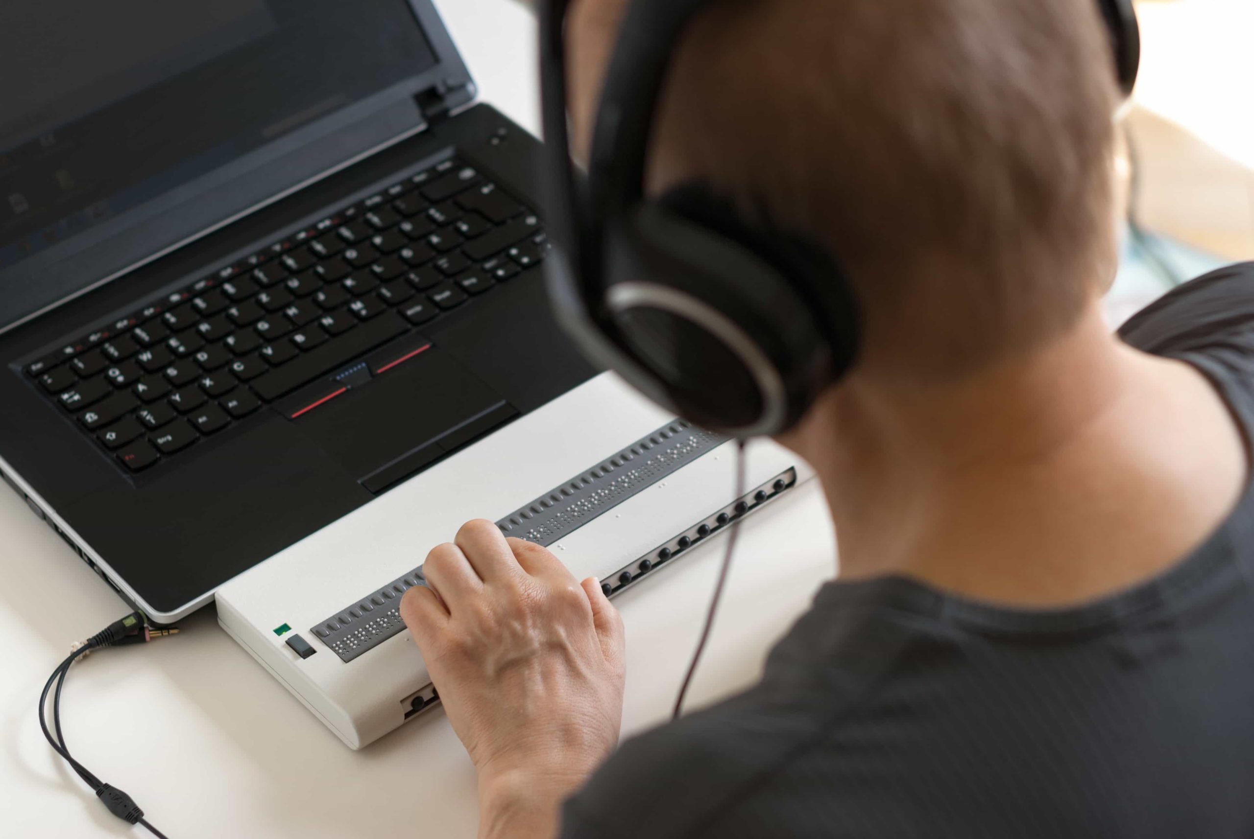 A man using a braille keyboard with a laptop.