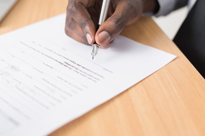 Closeup of someone's hand as they sign a document.