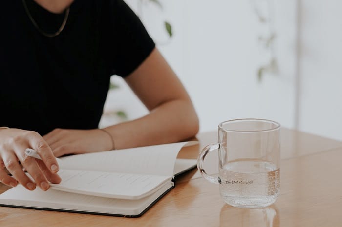 A person sitting at a table and writing in a planner