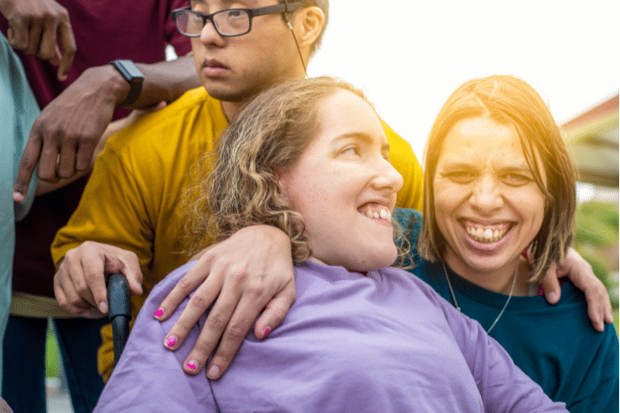 3 people smiling for a camera outside.