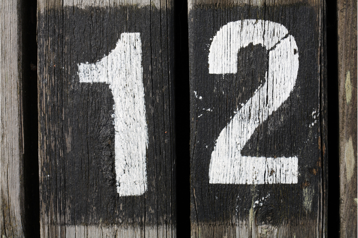 The number twelve in white paint on wood.