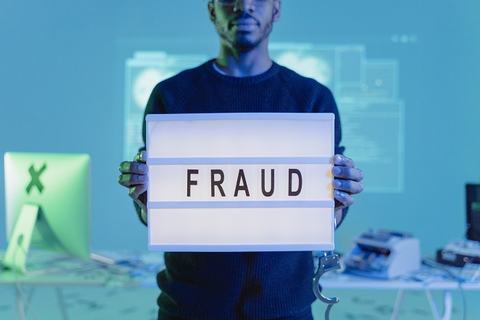 A man holds a sign that says 'fraud'