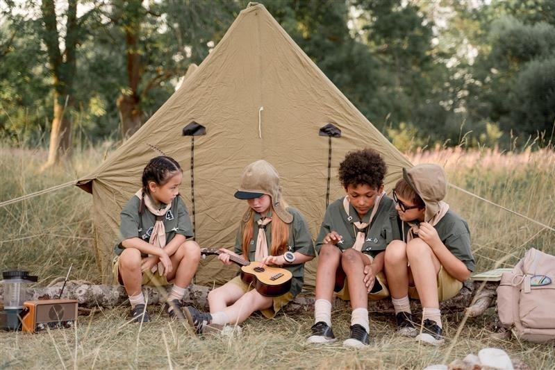 Four children dressed in Scouts uniforms are on a camp in the bush.