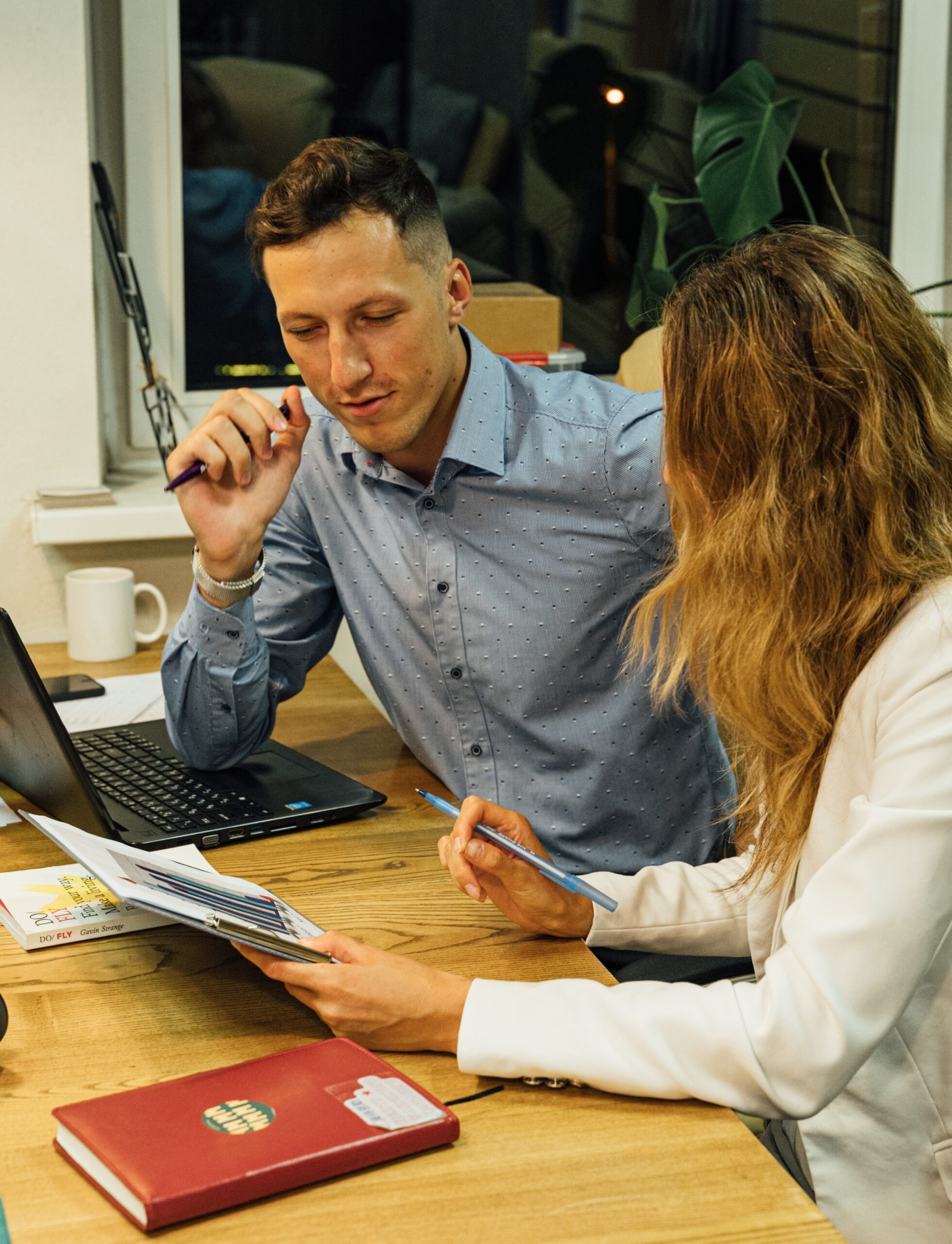 Two professionals having a discussion at a desk.