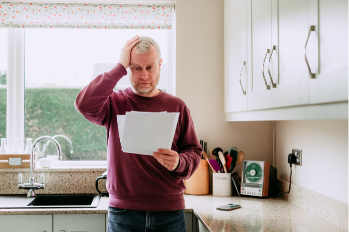 A stressed person looks at bills in disbelief.