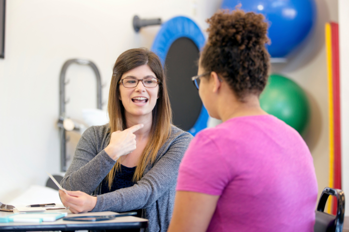 A speech pathologist supports her client in a 1:1 session.