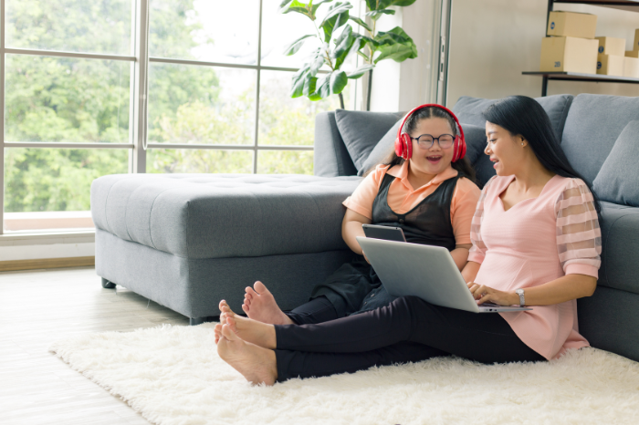 A mother and daughter sit together on their lounge room floor.