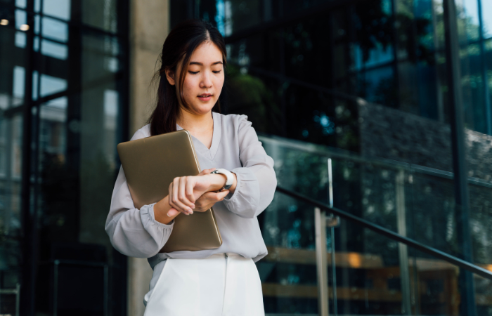 A woman looks at the time on her wrist watch.