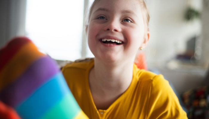 A close up of a happy girl in a yellow sweater.