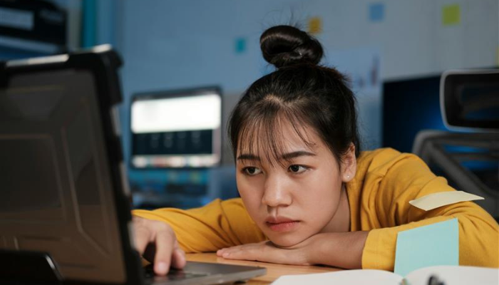 A person looking defeated in front of a laptop.